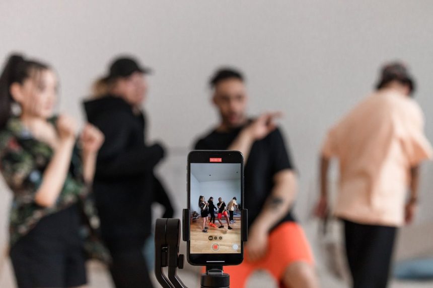 Grupo de dançarinos grava uma apresentação com um smartphone apoiado em um tripé.