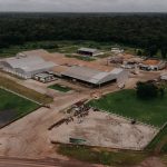 Vista aérea de uma planta industrial com galpões e áreas verdes ao redor