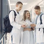 Grupo de estudantes de medicina de jaleco estuda em um corredor hospitalar.