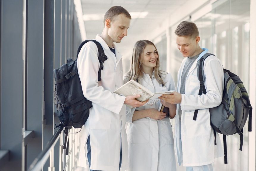 Grupo de estudantes de medicina de jaleco estuda em um corredor hospitalar.