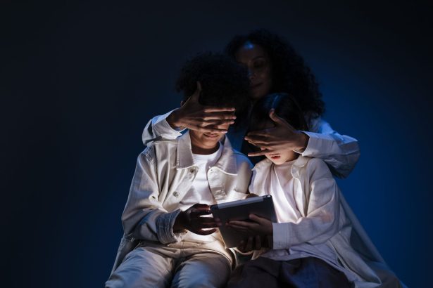 Mãe acompanha duas crianças enquanto elas usam um tablet em casa, representando supervisão e segurança infantil no ambiente digital.