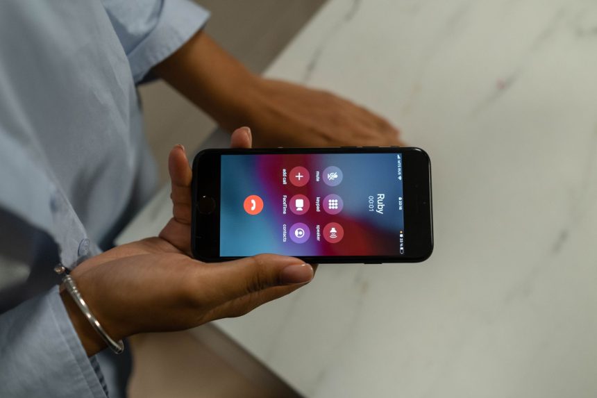Pessoa segura um smartphone com a tela exibindo uma chamada recebida.